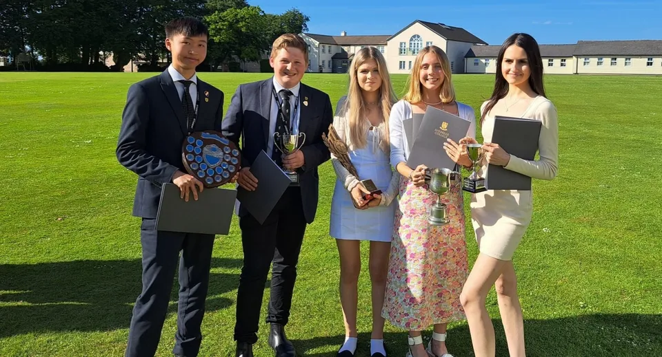 Un gruppo di cinque studenti si trova su un prato davanti all'edificio del Shebbear College.