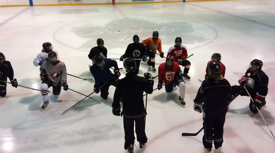 Studenti della Bracebridge and Muskoka Lakes Secondary School si trovano con diverse maglie sulla pista di ghiaccio con un grande logo al centro.