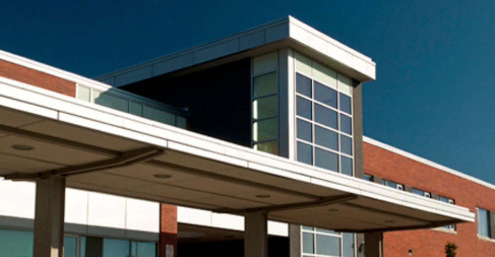 L'edificio moderno a più piani della Maxwell Heights Secondary School con facciata in vetro e mattoni sotto un cielo azzurro e limpido.