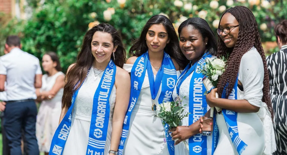 Studentesse della Marymount Academy International sono all'aperto in un giardino verde e sorridono insieme.