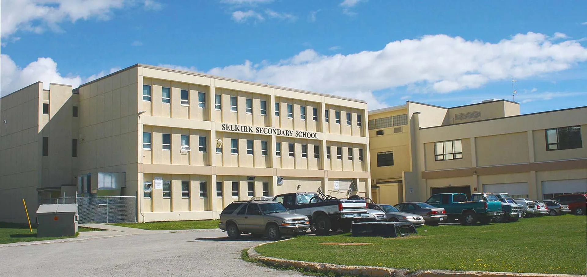 L'edificio beige a più piani della Selkirk Secondary School con auto parcheggiate sul davanti.