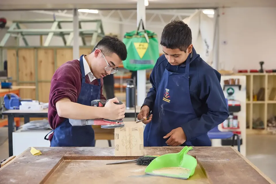 Due studenti della Cobram Anglican Grammar School lavorano a un oggetto di legno in un laboratorio con una levigatrice.