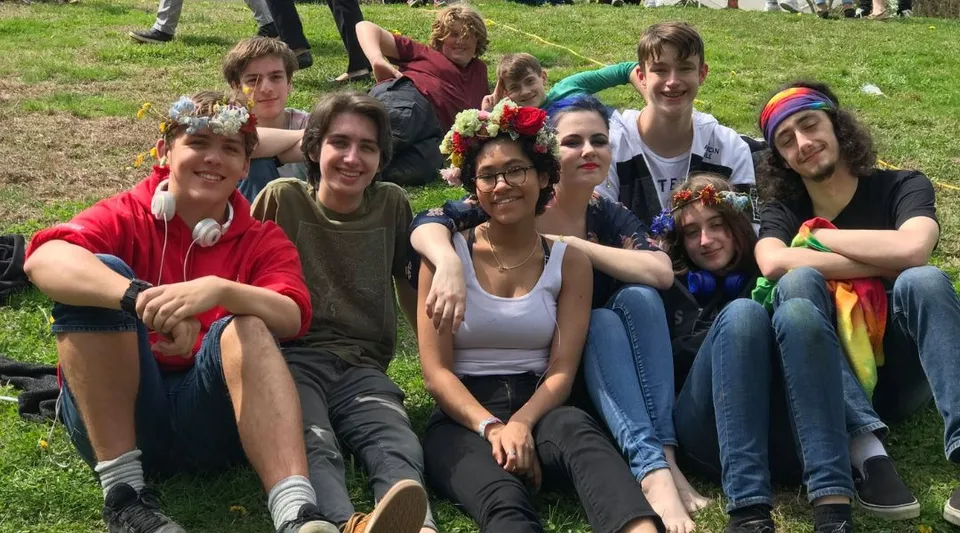 Un gruppo di studenti siede insieme sull'erba in un'area esterna della Sparhawk School.
