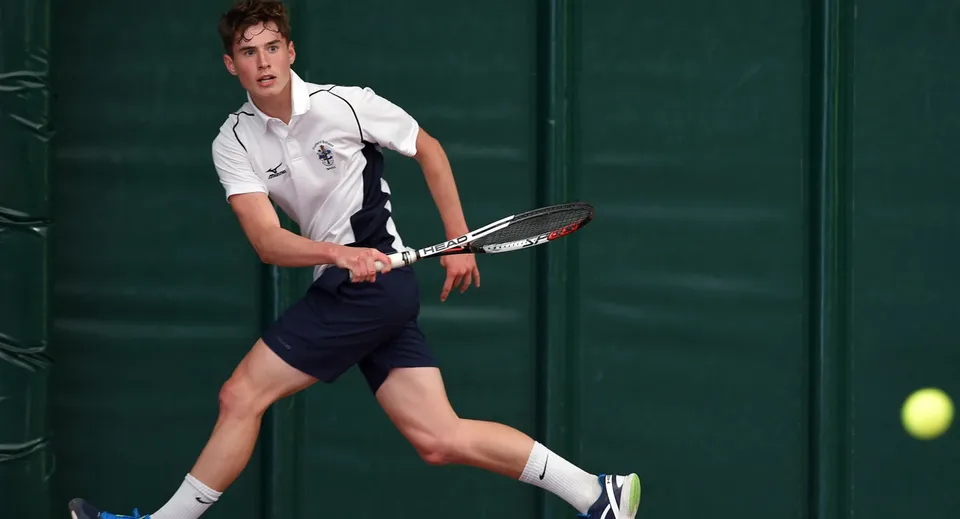 Un giovane tennista si prepara a un colpo sul campo da tennis della Culford School.