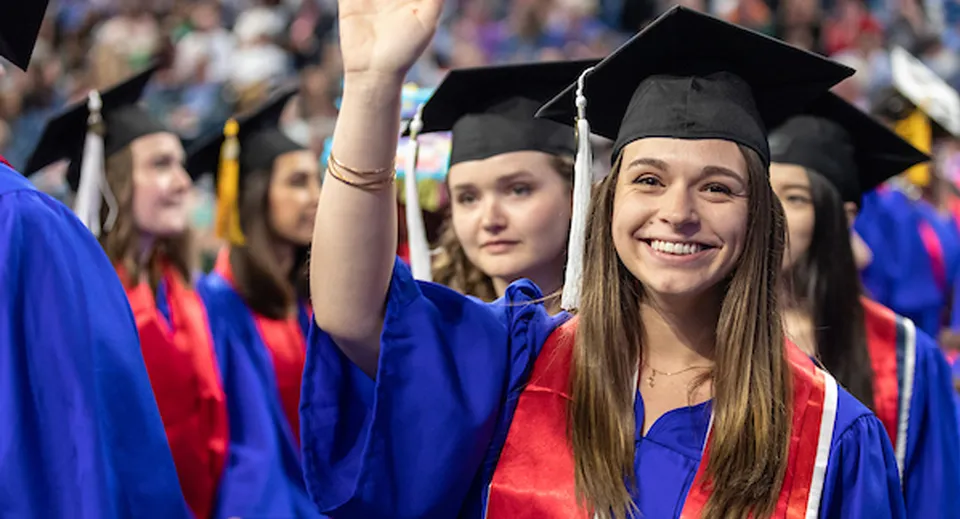 Un gruppo di diplomate e diplomati delle Chicago Public Schools è insieme con le toge di laurea blu e rosse.