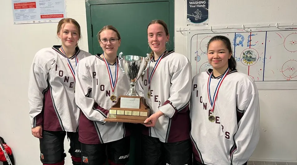 La squadra sportiva della Queen Elizabeth Regional High tiene in mano un trofeo nello spogliatoio.