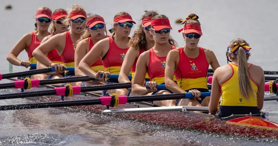 La squadra di canottaggio della St. Hilda’s School rema insieme su un'imbarcazione.
