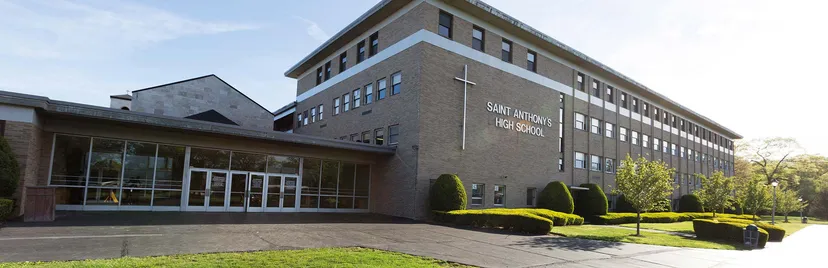 L'edificio in mattoni della Saint Anthony's High School con una croce sulla facciata e un viale d'ingresso decorato con piante.