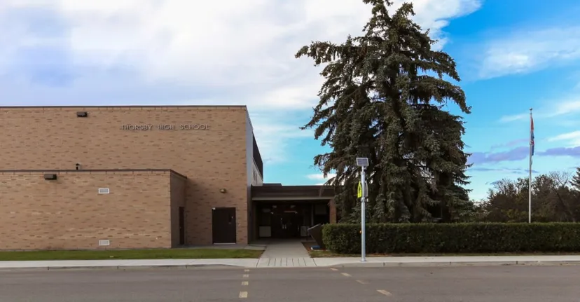 L'edificio in mattoni della Thorsby Junior Senior High School con un grande ingresso e un'alta conifera in primo piano.