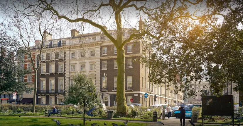 L'edificio storico della Guildhouse School London dietro alberi e un'area verde.