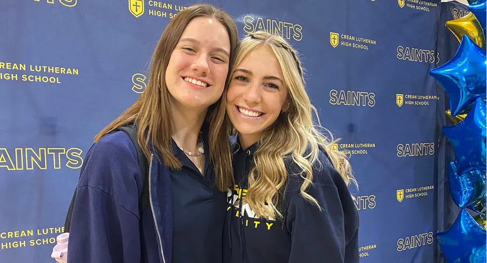 Due studentesse sorridenti con i capelli lunghi e biondi si trovano davanti a uno sfondo con il logo della Crean Lutheran High School.