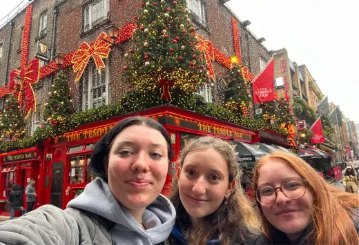 Drei Mädchen machen ein Selfie vor dem weihnachtlich geschmückten Temple Bar in Dublin