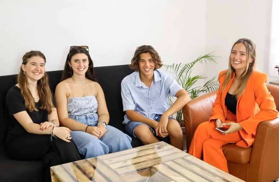Tre giovani e una donna sorridono seduti insieme su un divano durante un colloquio