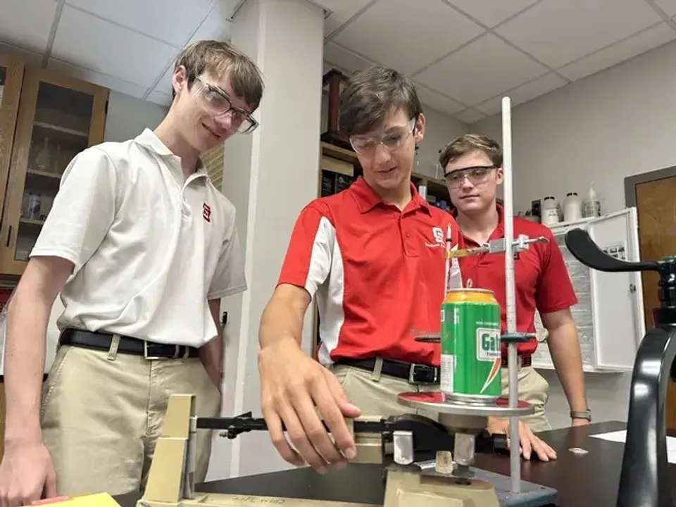 Tre studenti della Saint Stanislaus Catholic High School eseguono un esperimento con occhiali protettivi nel laboratorio di scienze.