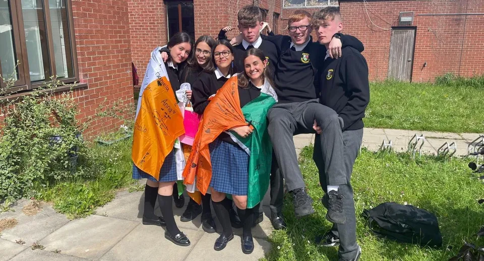 Un gruppo di studenti è in piedi su un prato davanti a un edificio in mattoni nel campus del St. Finian’s Community College.