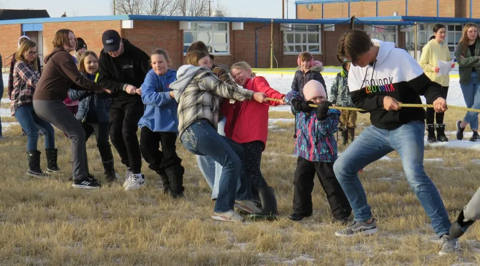 Studenti della Huntsville School partecipano a un'attività di squadra all'aperto su un prato accanto a un edificio in mattoni.