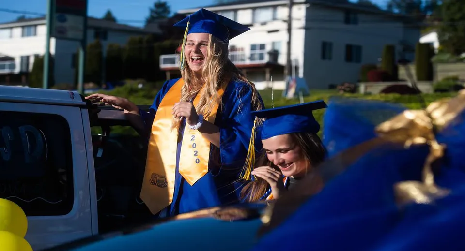 Due diplomate sorridenti di Tacoma Public Schools con toga e tocco blu all'aperto.