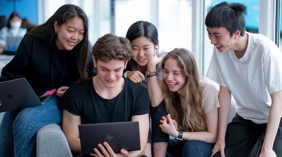 Studenti dell'Oxford International College Brighton lavorano insieme a un laptop.