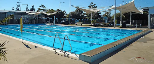 La gran piscina en el área exterior del Ballajura Community College está rodeada de zonas de asiento a la sombra y árboles.