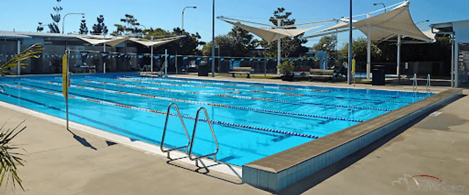 La grande piscina all'aperto del Ballajura Community College è circondata da zone d'ombra con sedute e alberi.