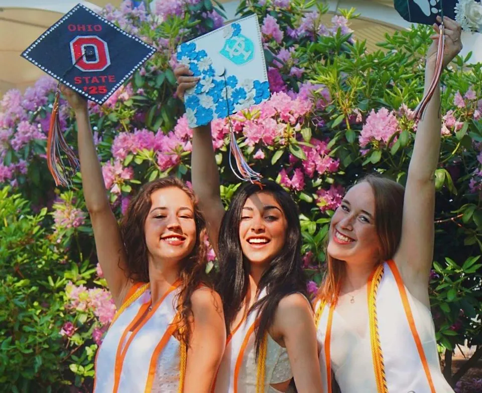 Tre studentesse della Hopkinton High School in posa davanti a uno sfondo floreale colorato.
