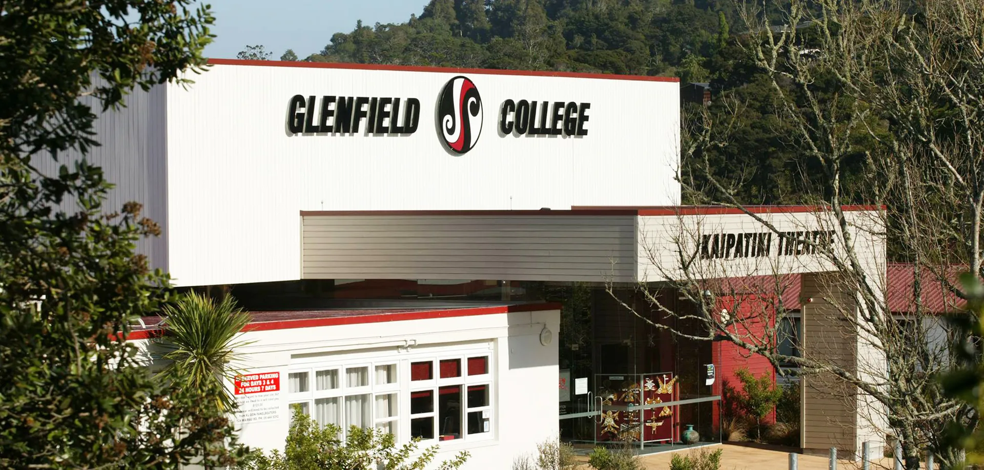 L'edificio del Glenfield College con una grande insegna è circondato da alberi e altri edifici.