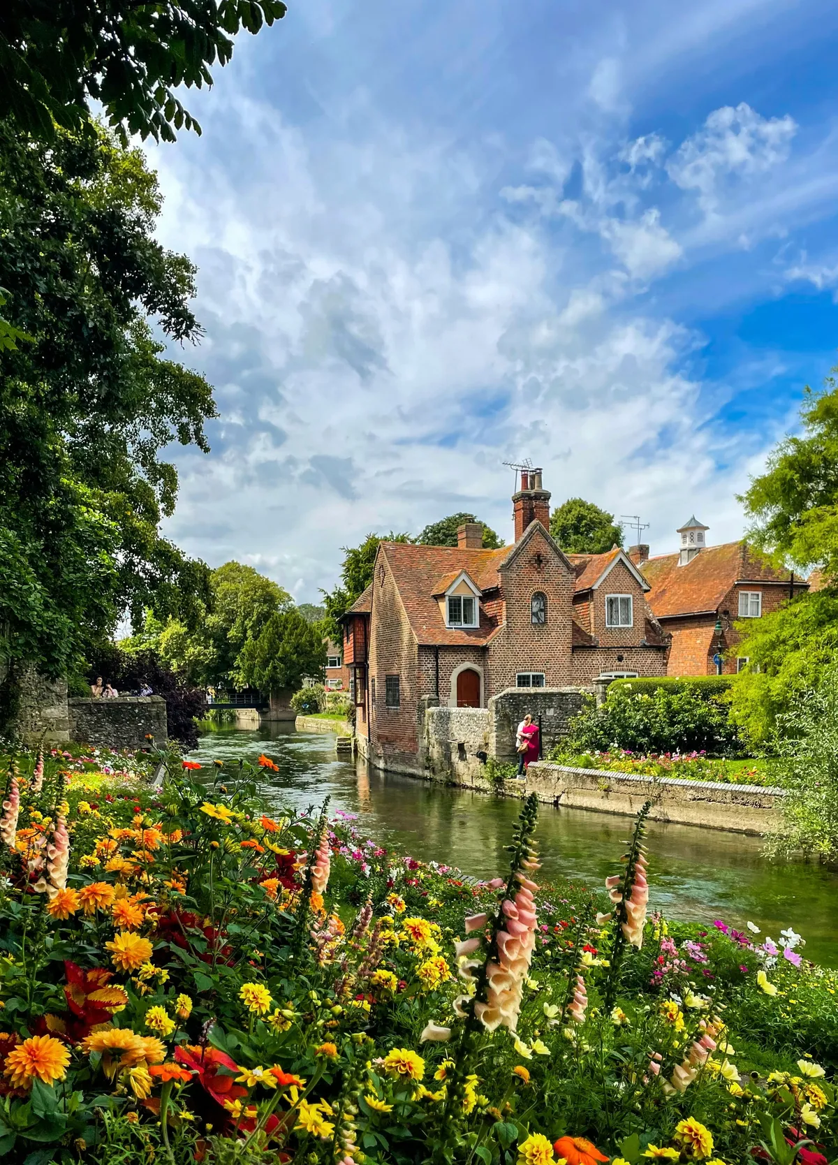 Casa de ladrillo junto al río Stour en Canterbury con flores de verano en primer plano