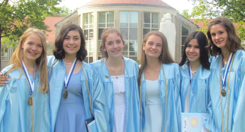 Un gruppo di diplomande in toga blu si trova davanti a un edificio con cupola nel campus del Dominican College Wicklow.