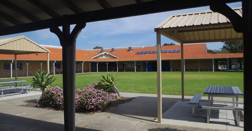 Area esterna coperta con panchine e tavoli nel campus della Ocean Reef Senior High School.