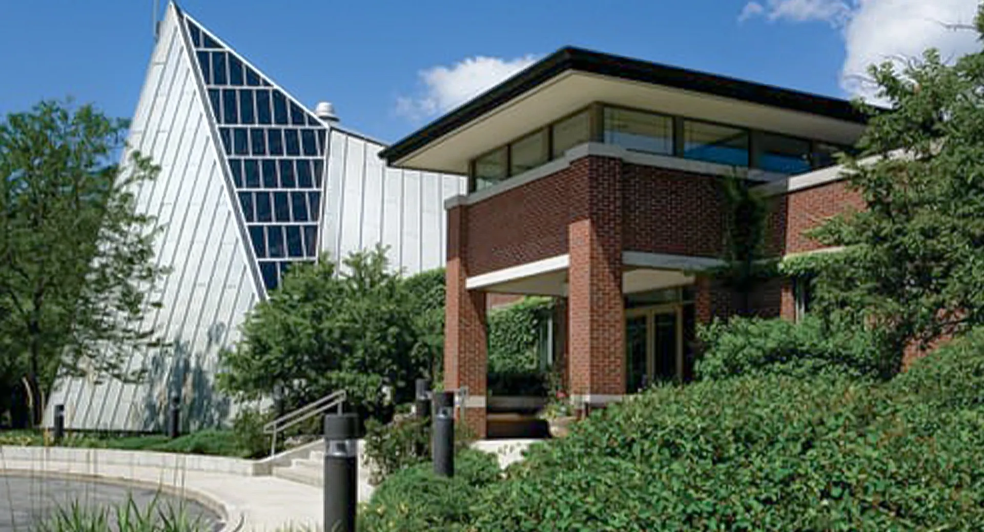 Il moderno edificio a più piani con facciata in vetro della Woodlands Academy of the Sacred Heart è circondato da alberi e da un paesaggio ben curato.