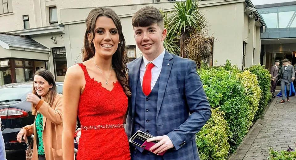 Una giovane coppia davanti a un edificio con piante verdi nei terreni della Scoil Mhuire (Strokestown).