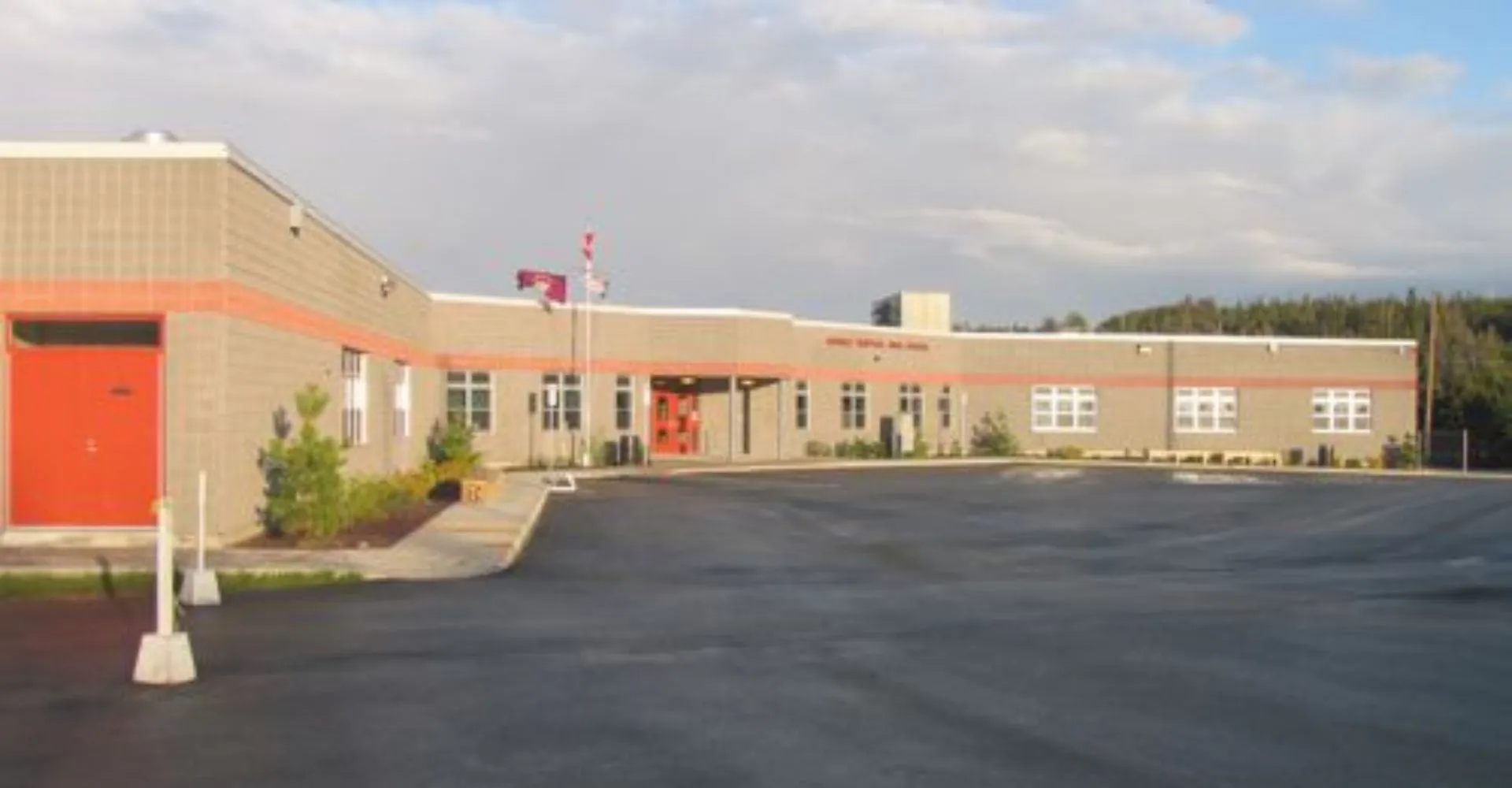 Si vede il moderno edificio a più piani della Mobile Central High, con la porta d'ingresso rossa e la bandiera canadese.