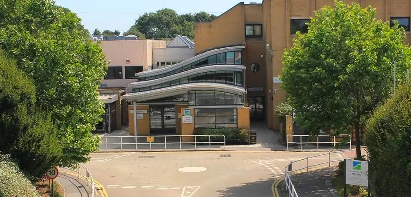 L'edificio moderno del South Downs College è circondato da alberi verdi ed è raggiungibile tramite un viale pavimentato.
