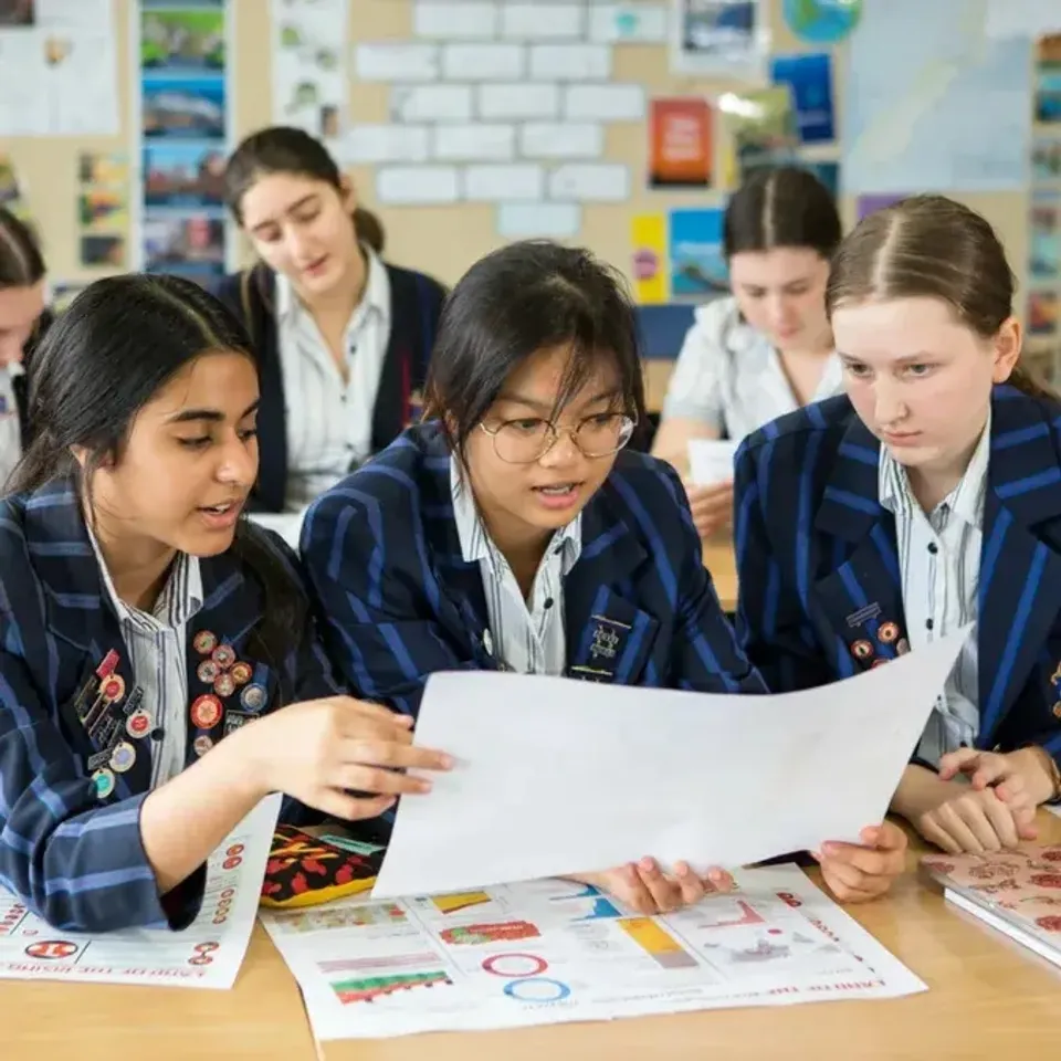 Un gruppo di studentesse della Diocesan School For Girls lavora insieme, concentrate su un documento al tavolo.