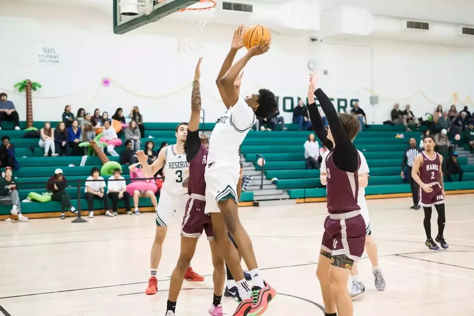 Un giocatore di pallacanestro della Western Reserve Academy salta verso il canestro durante una partita in palestra.