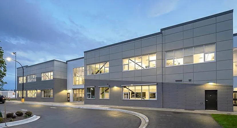 L'edificio scolastico moderno a più piani della Langley Secondary School con ampie finestre e un viale d'accesso curvo sotto un cielo nuvoloso.