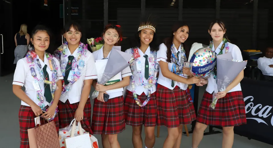 Un gruppo di studentesse in tradizionali divise scolastiche giapponesi insieme sul campus della MacGregor State High School.