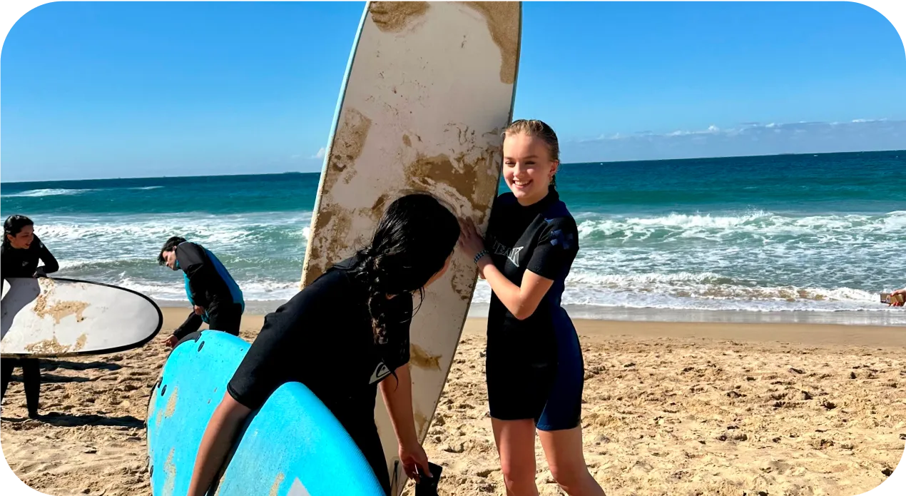 Dos chicas con traje de neopreno sujetan sus tablas de surf en la orilla de la playa