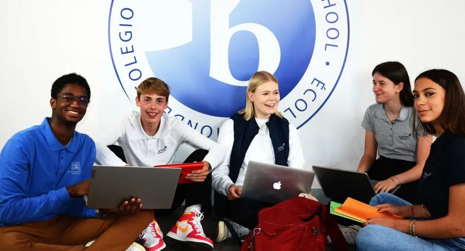 Un gruppo di studenti con laptop è seduto insieme sul campus della Episcopal Sem' De Walbourg.