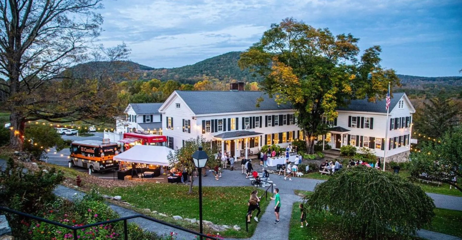 L'edificio bianco della South Kent School con persone e food truck radunati nel cortile.