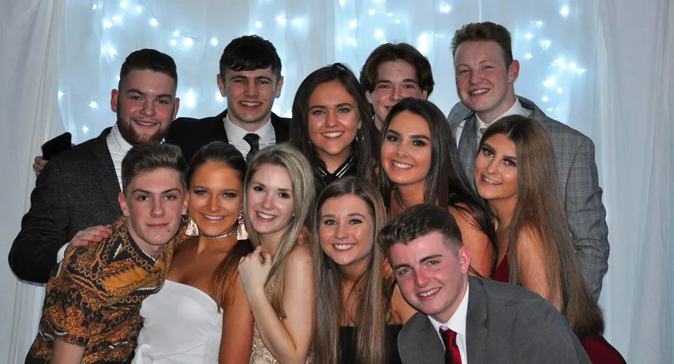 Un gruppo di studenti e studentesse della Musselburgh Grammar School posa davanti a uno sfondo con luci scintillanti.