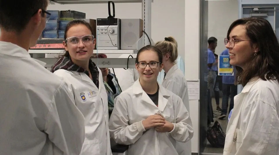 Studenti della Huntsville School conversano in camici bianchi da laboratorio all'interno di un laboratorio.