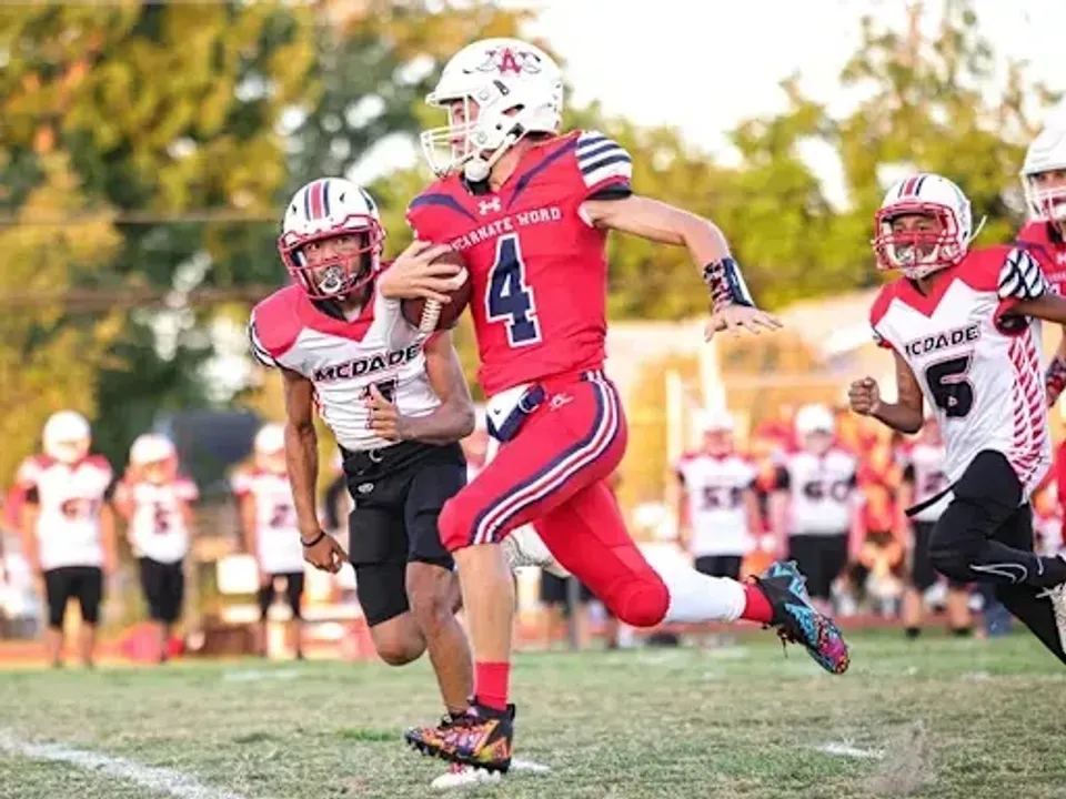 Gli studenti della Incarnate Word Academy giocano a calcio sul campo sportivo con il pubblico sullo sfondo.