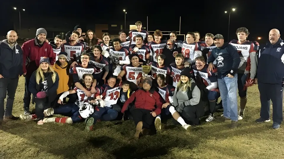 Un grande gruppo di studenti della École Camrose Composite High School si riunisce di notte su un campo con maglie sportive e cartelli.