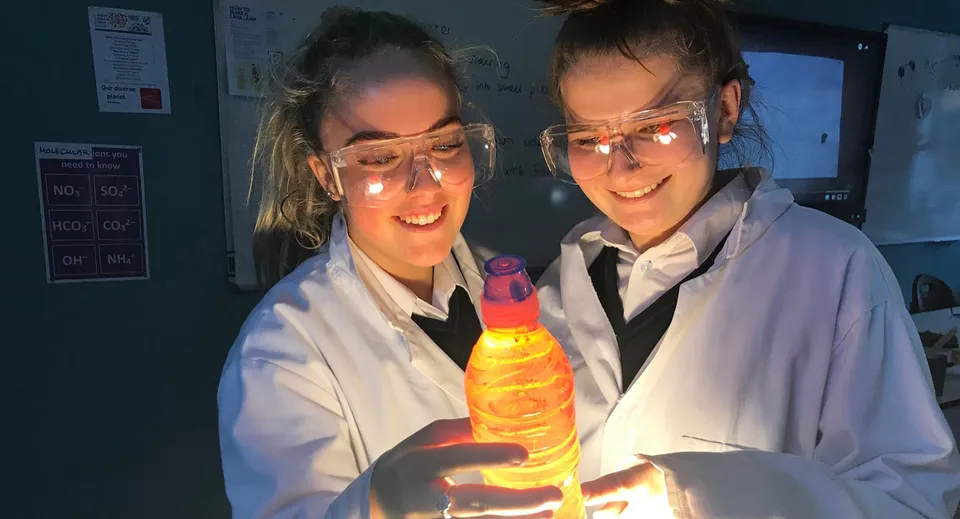 Due studenti della Adcote School in laboratorio tengono un oggetto giallo luminoso durante un esperimento.