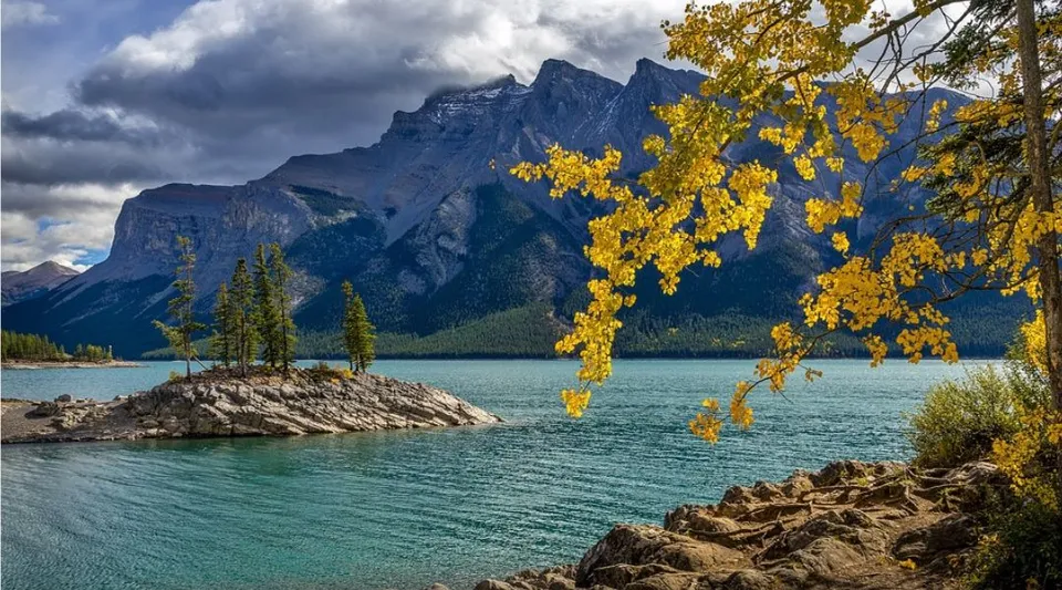 Vista su un lago tranquillo con montagne e fogliame autunnale nelle vicinanze della Tofield School.