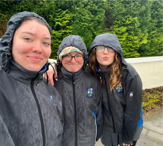 Drei Mädchen in Regenjacken machen ein Selfie im Regen in Irland
