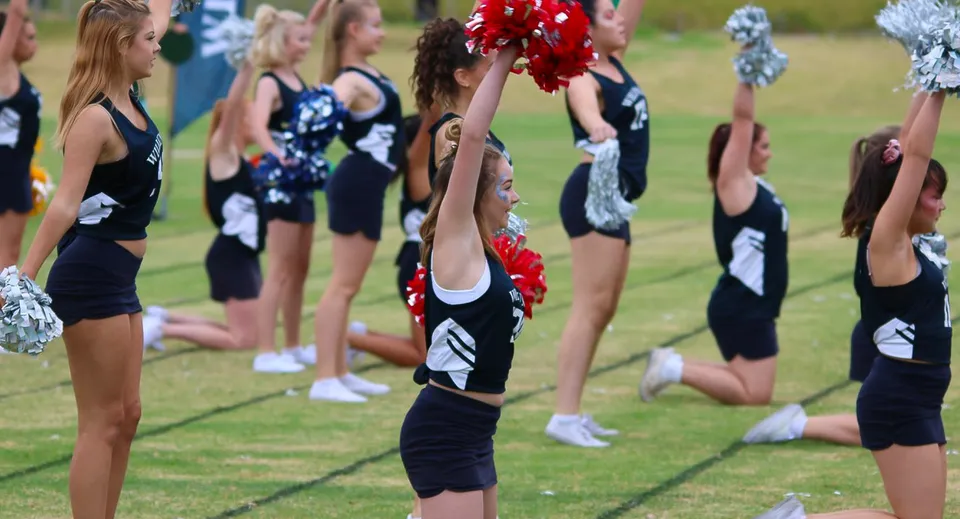 Un gruppo di cheerleader esegue una routine sincronizzata sul campo in erba della Willunga High School.