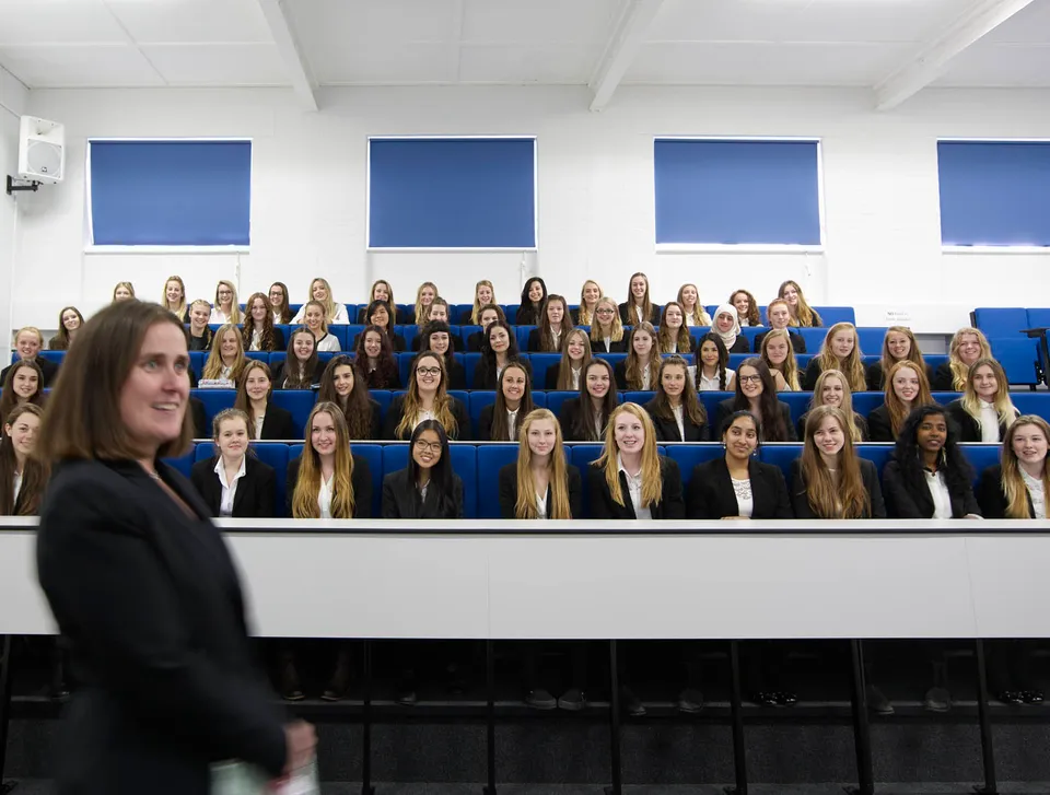 Studentesse sedute in un'aula della Torquay Girls Grammar School davanti a finestre con cornici blu.