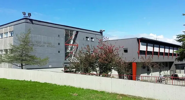 El moderno edificio de varias plantas de la Eric Hamber Secondary School con fachadas de cristal y hormigón se encuentra en un terreno de césped con árboles.